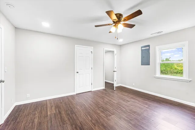 a view of an empty room with window and wooden floor