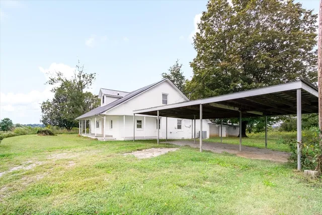 a view of house with a big yard and large trees