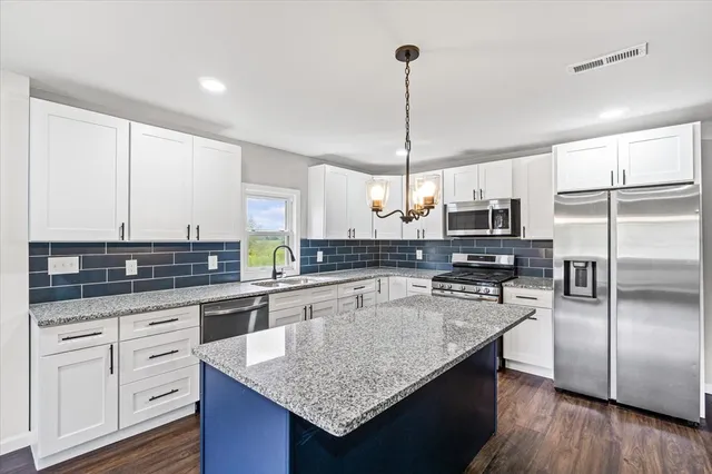 a kitchen with stainless steel appliances granite countertop a sink a stove refrigerator and cabinets