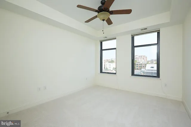 an empty room with windows and fan
