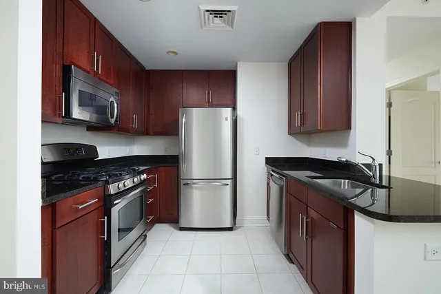 a kitchen with stainless steel appliances granite countertop a stove top oven a refrigerator a sink and dishwasher