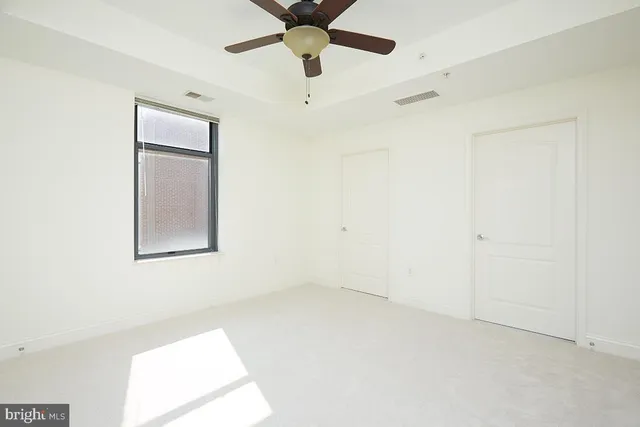 an empty room with a window and a fan