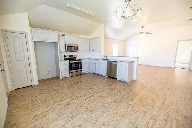 a large kitchen with cabinets wooden floor and stainless steel appliances