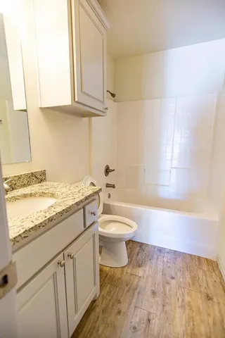 a bathroom with a granite countertop toilet a sink and a bathtub