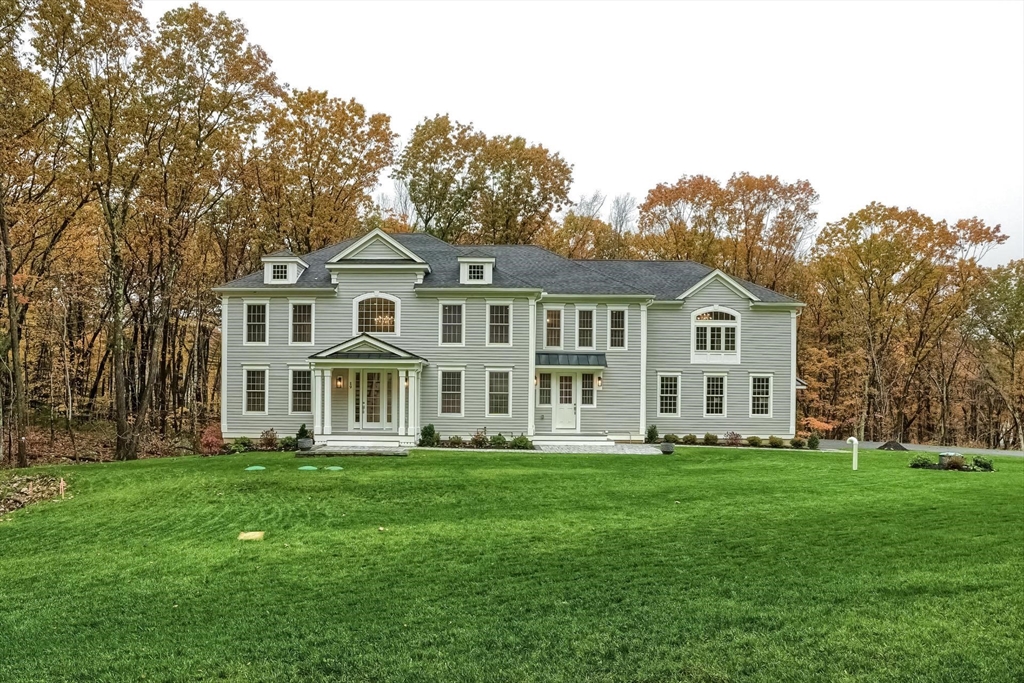 a front view of a house with a garden and trees