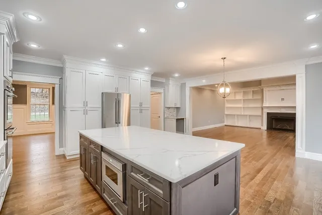 a large kitchen with kitchen island a stove a refrigerator a sink dishwasher with a dining table and chairs with wooden floor