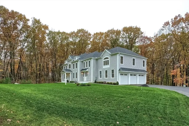 a front view of a house with a garden and trees