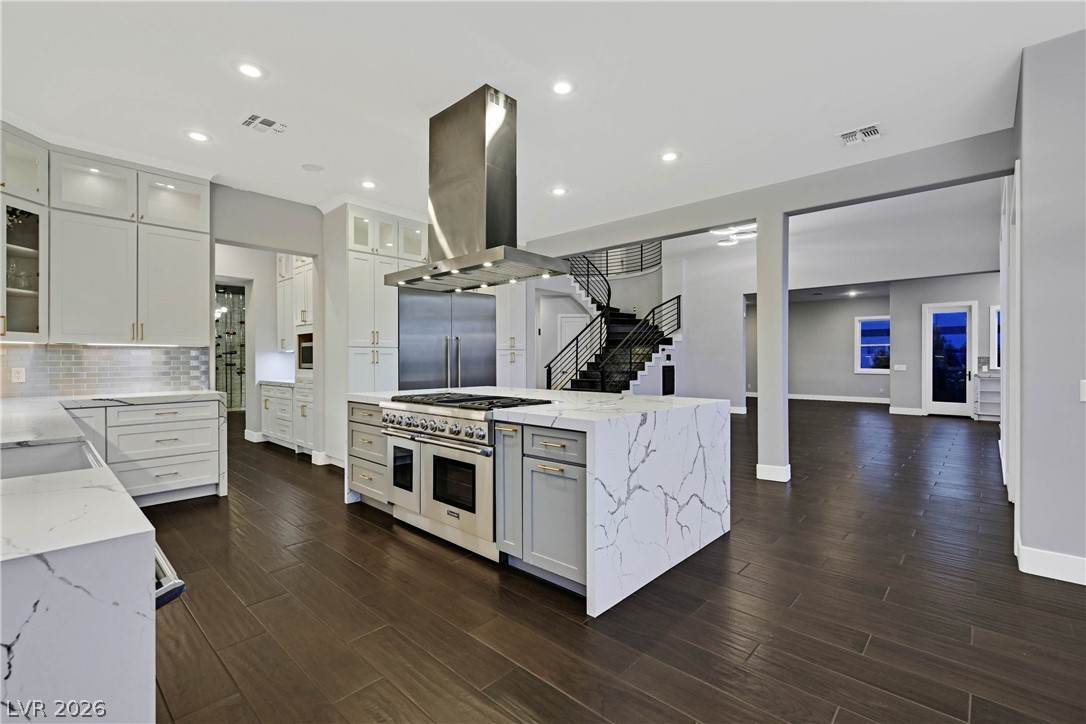 6 Rue Du Ville Henderson, NV 89011 - Photo 39 of 99 This kitchen showcases a central island and a striking staircase, blending modern design with functional elegance.