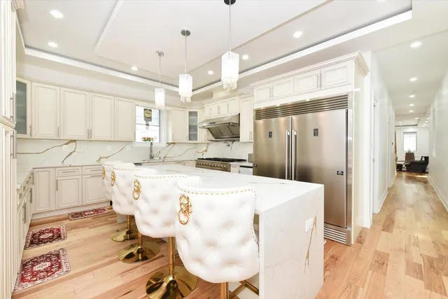 a large kitchen with kitchen island a stove a sink dishwasher and a refrigerator with wooden floor