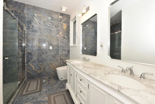 a bathroom with a granite countertop sink toilet and shower