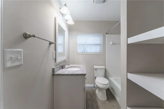 a bathroom with a granite countertop sink a toilet and a mirror