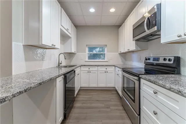 a kitchen with granite countertop a sink a stove and cabinets