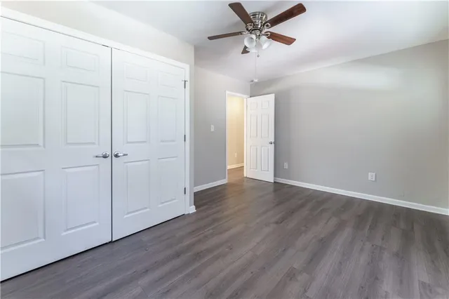 an empty room with wooden floor closet and windows