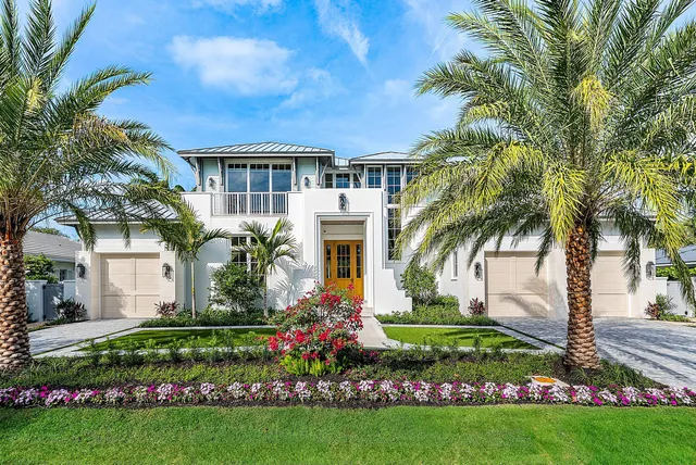 a front view of yellow house with a garden and plants