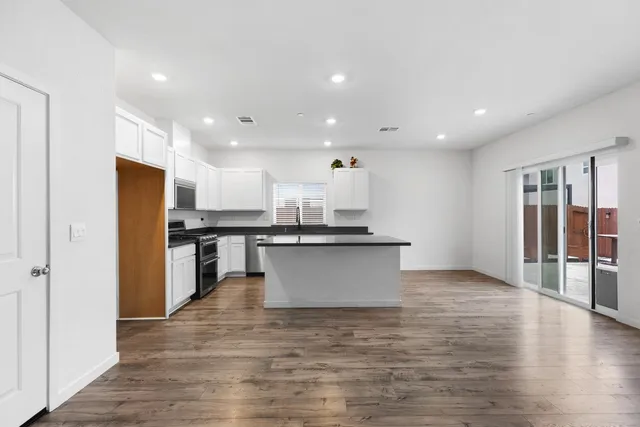 a view of kitchen with stainless steel appliances wooden floor and large window