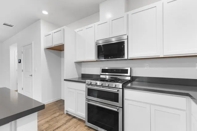 a kitchen with stainless steel appliances a stove a microwave and white cabinets