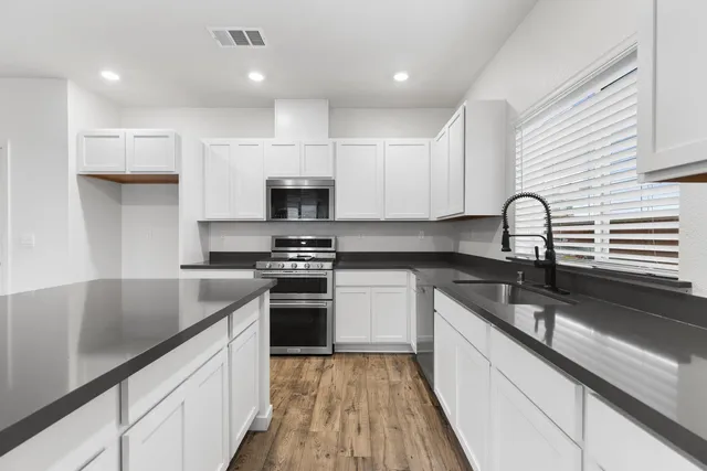 a kitchen with kitchen island granite countertop a sink appliances cabinets and a counter top space