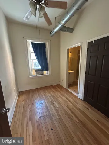 an empty room with wooden floor closet and windows