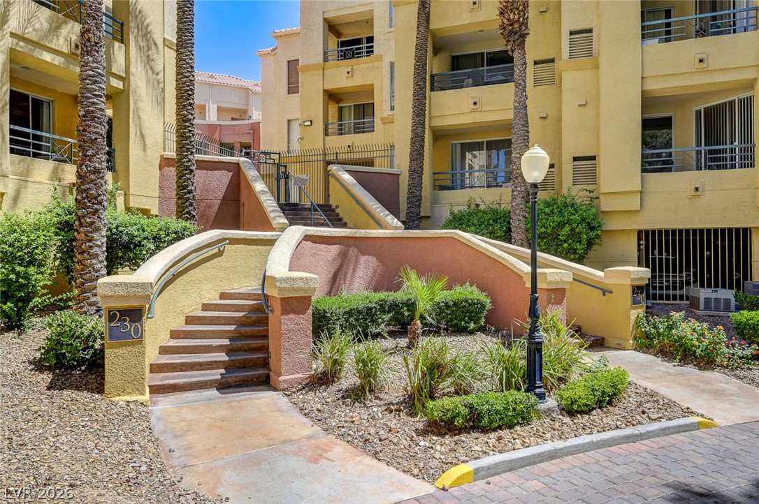 230 East Flamingo Road, Unit 106 Las Vegas, NV 89169 - Photo 31 of 66 A welcoming entry path leads to an apartment complex featuring multi-level outdoor stairs and well-maintained landscaping.