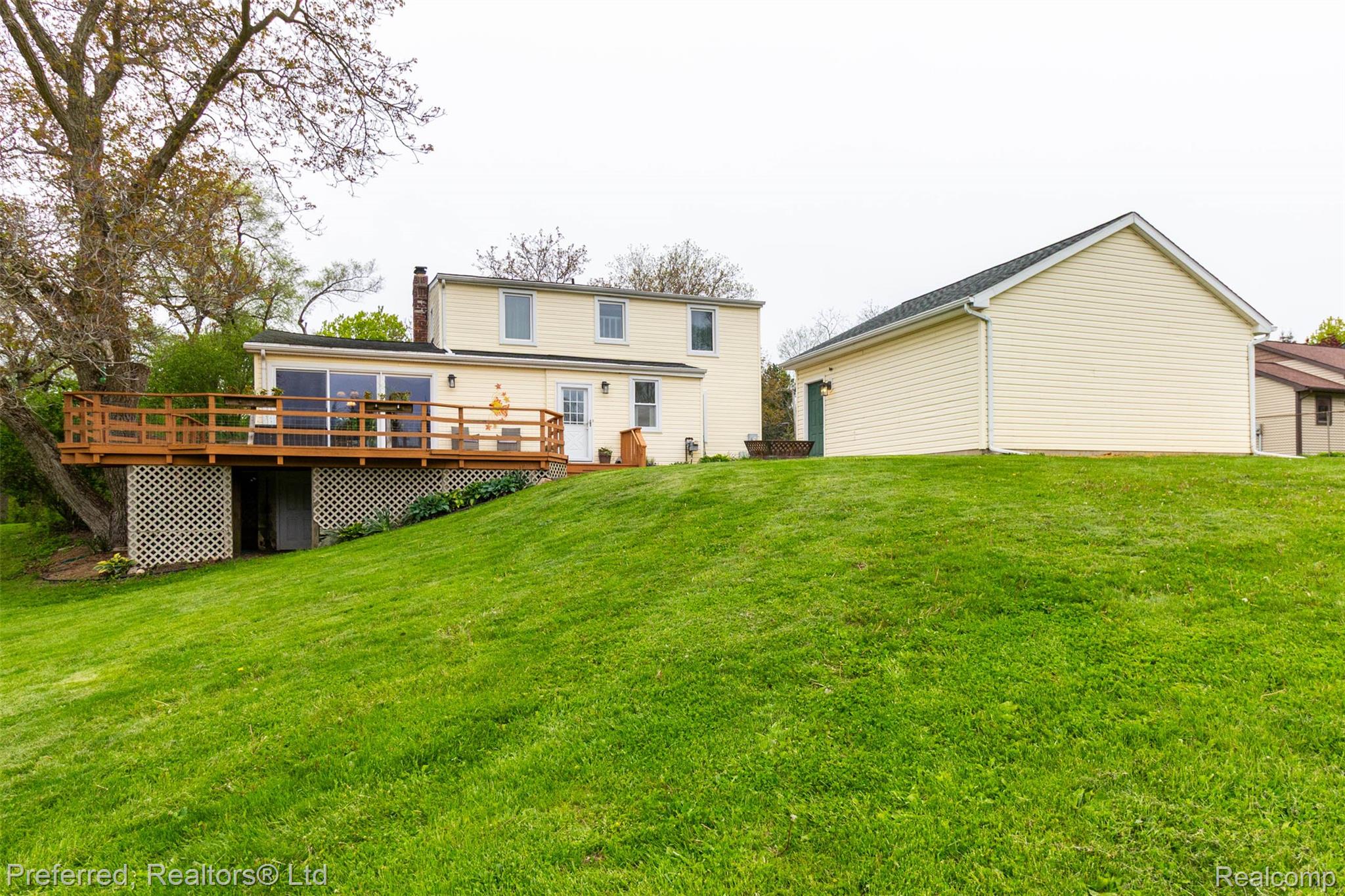 9840 Currie Road Northville, MI 48167 - Photo 44 of 62 Back of house with a wooden deck, a lawn, and a chimney