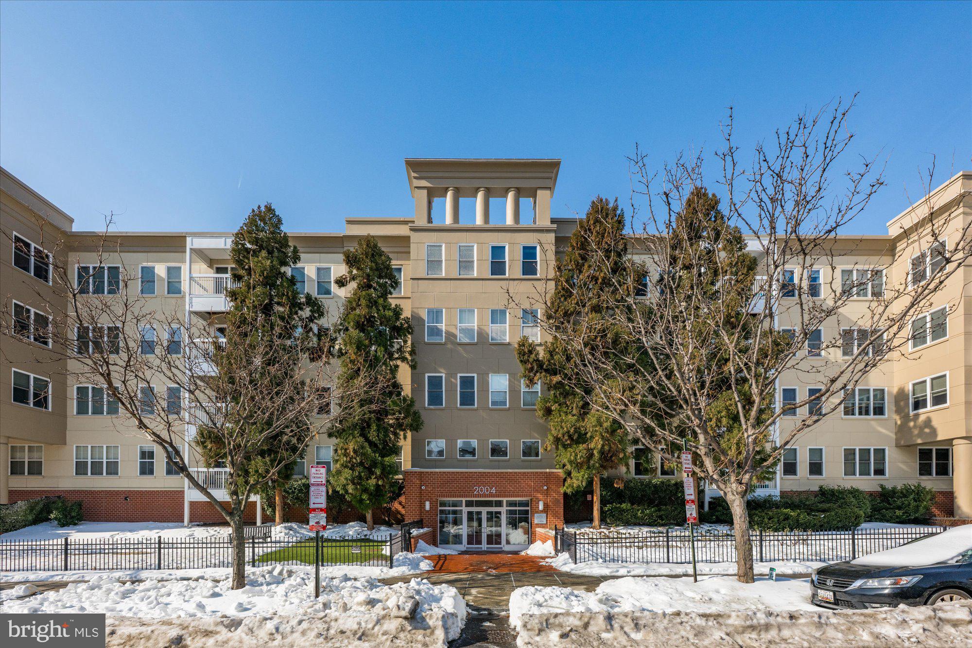 a front view of a building with lot of trees