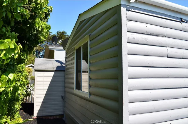 a view of a house with a large window couches and dinning table under an umbrella