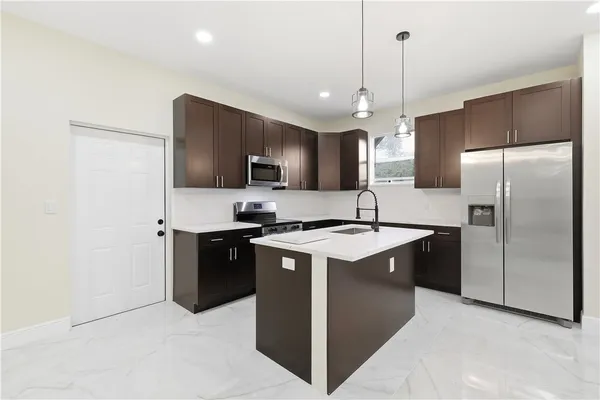 a kitchen with stainless steel appliances granite countertop a refrigerator a sink a stove a microwave and island