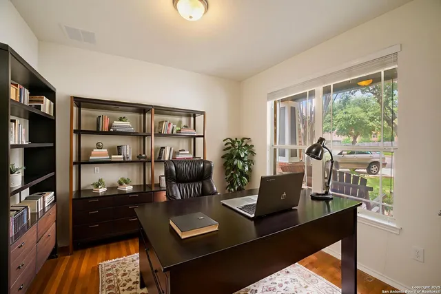 a view of an empty room with window and chandelier fan