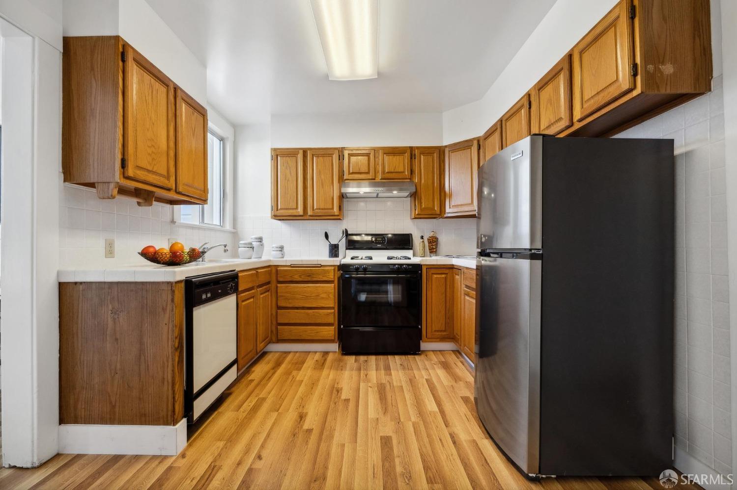 686 29th Avenue San Francisco, CA 94121 - Photo 36 of 69 a kitchen with stainless steel appliances granite countertop a refrigerator a sink dishwasher a stove and white countertops with wooden floor