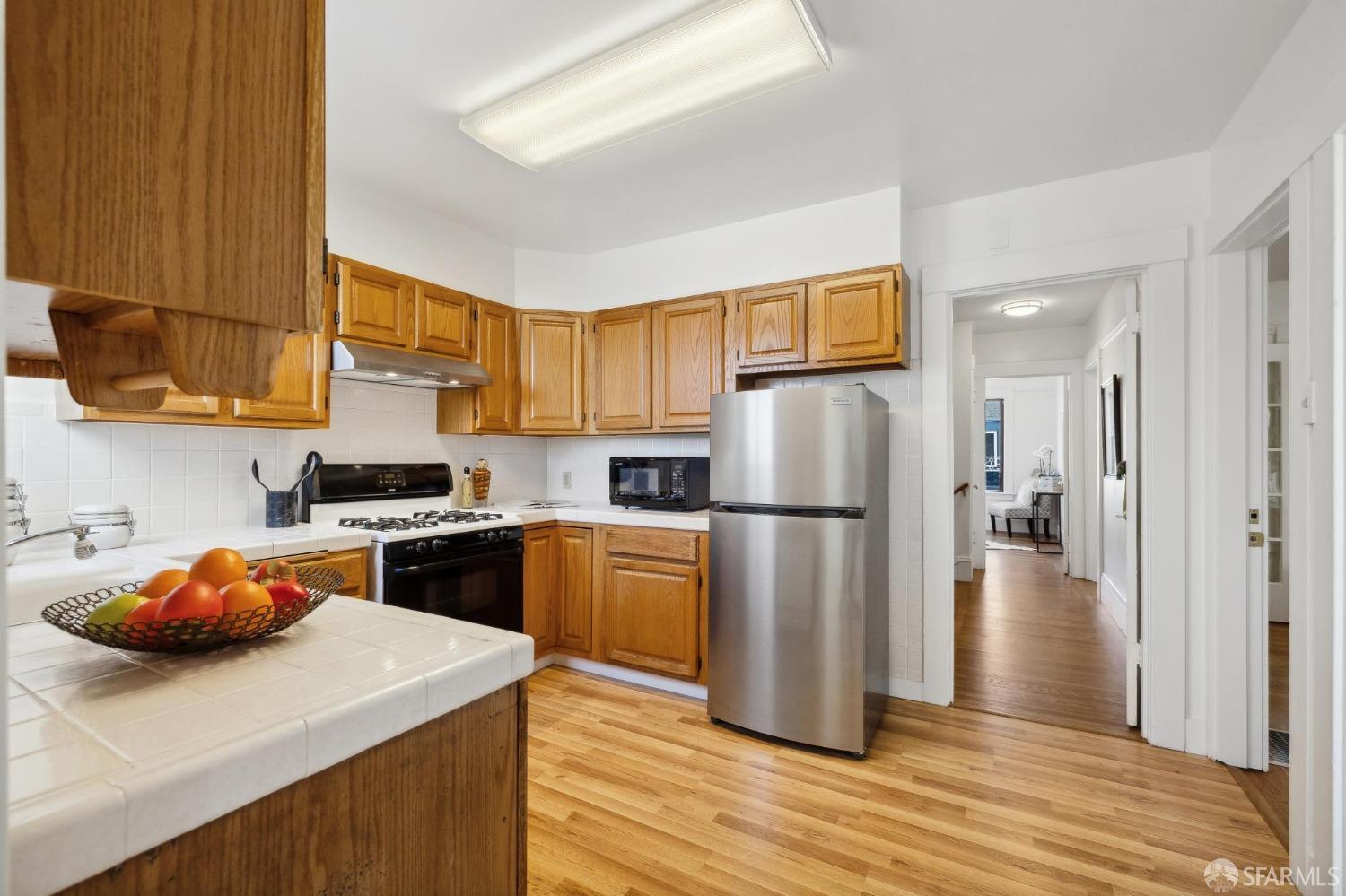 686 29th Avenue San Francisco, CA 94121 - Photo 38 of 69 a kitchen with stainless steel appliances granite countertop a refrigerator a sink dishwasher a stove with wooden floor and a cabinets