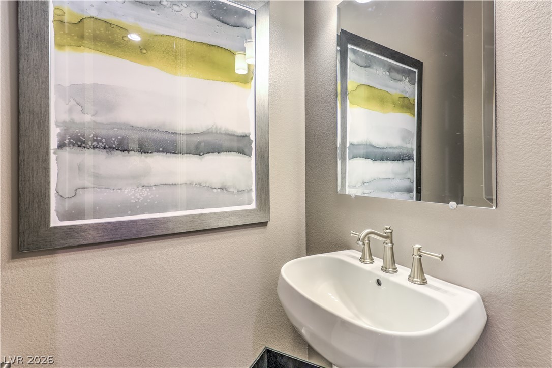 7119 Arabian Ridge Street Las Vegas, NV 89131 - Photo 25 of 73 A sleek pedestal sink and frameless mirror elevate this compact powder room.