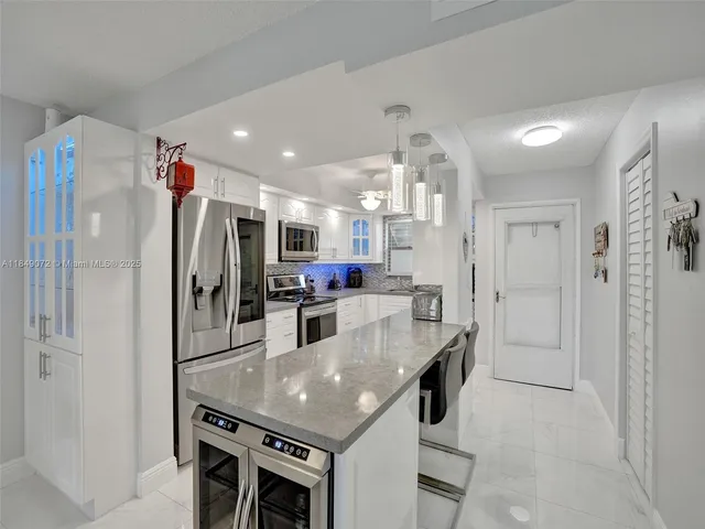 a kitchen with stainless steel appliances granite countertop a table chairs and a refrigerator
