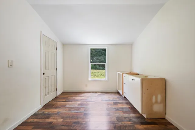 a view of hallway with window and wooden floor