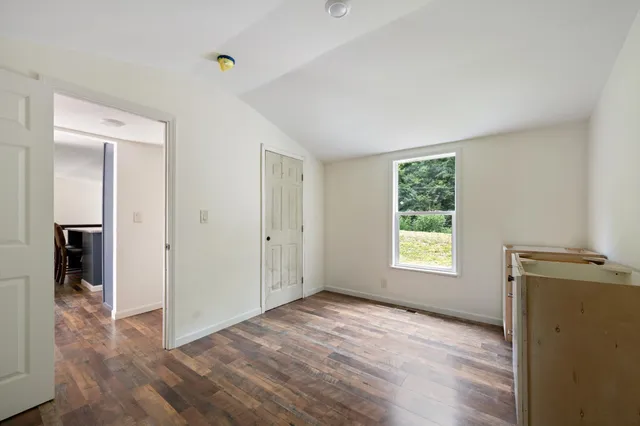 a view of an empty room with window and wooden floor