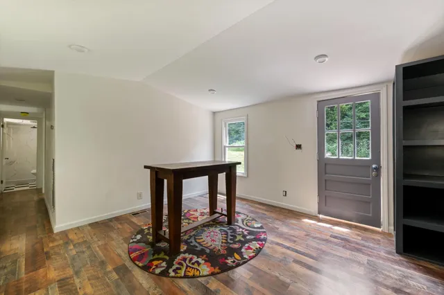 a living room with table chairs and a window