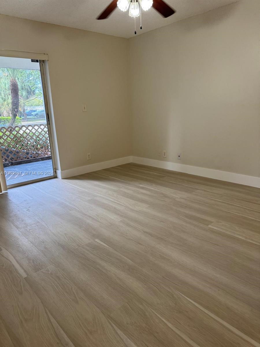 5760 Rock Island Road, Unit 304 Tamarac, FL 33319 - Photo 13 of 40 a view of an empty room with wooden floor and a window