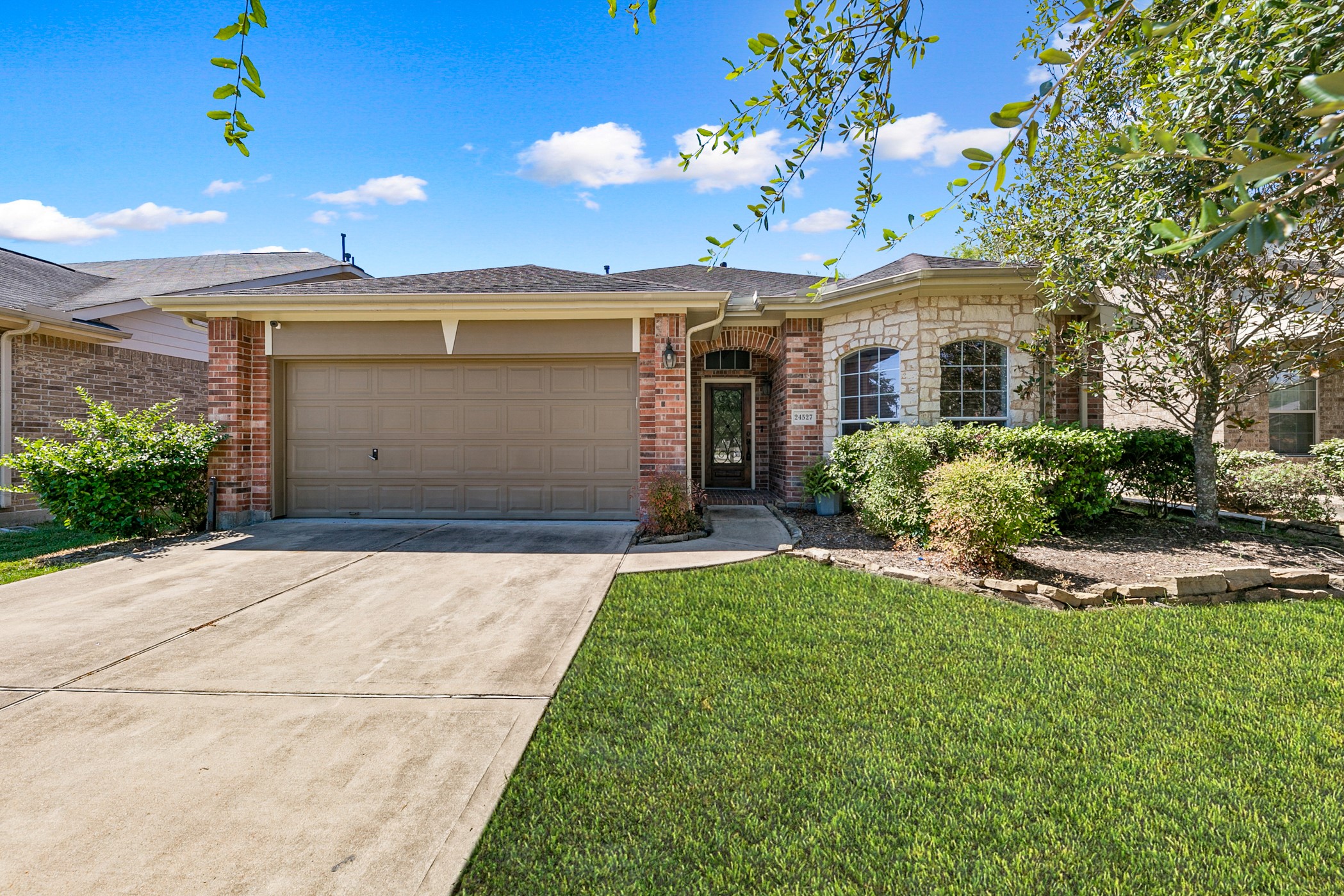 24527 Spring Harbor Drive Spring, TX 77373 - Photo 1 of 22 This charming home features a brick and stone exterior with a well-maintained front yard. It includes a two-car garage and a welcoming front entrance surrounded by lush greenery.