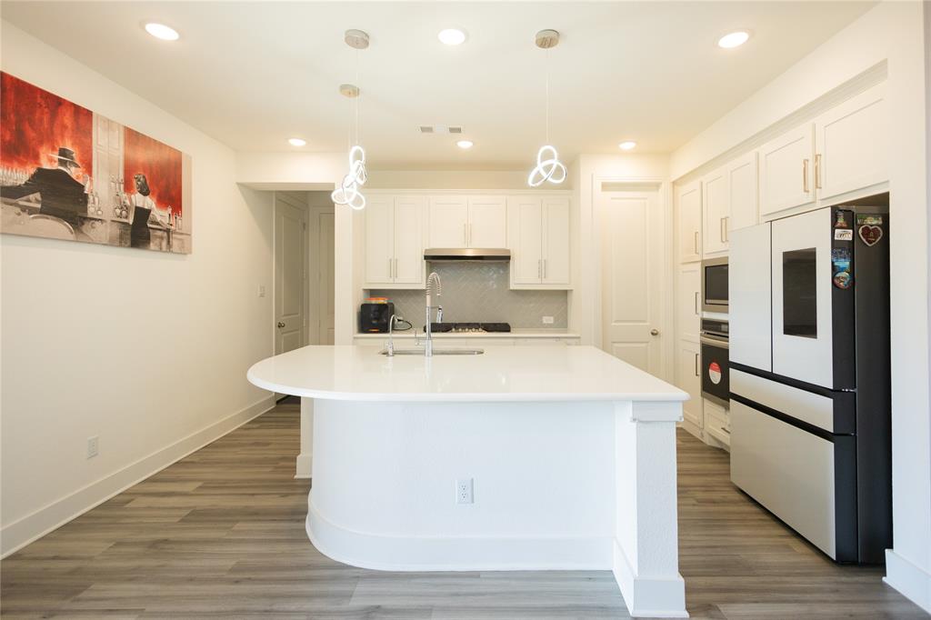3017 Andorra Road McKinney, TX 75071 - Photo 12 of 40 Kitchen featuring a large central island, white cabinetry, a built-in refrigerator, and wood-finish flooring