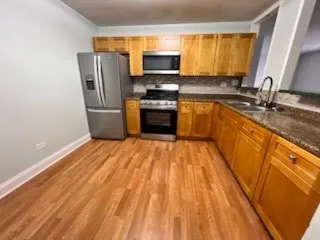 a kitchen with granite countertop a stove a sink and a refrigerator
