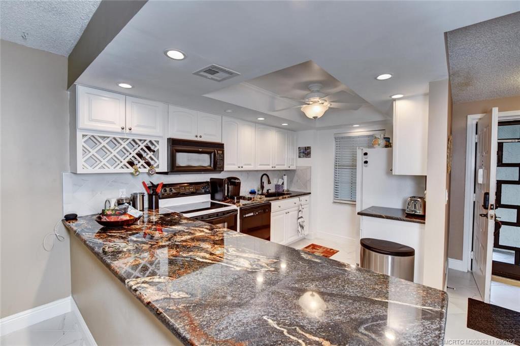 3100 Southeast Pruitt Road, Unit B102 Port St. Lucie, FL 34952 - Photo 12 of 55 a kitchen with stainless steel appliances granite countertop a sink stove and refrigerator