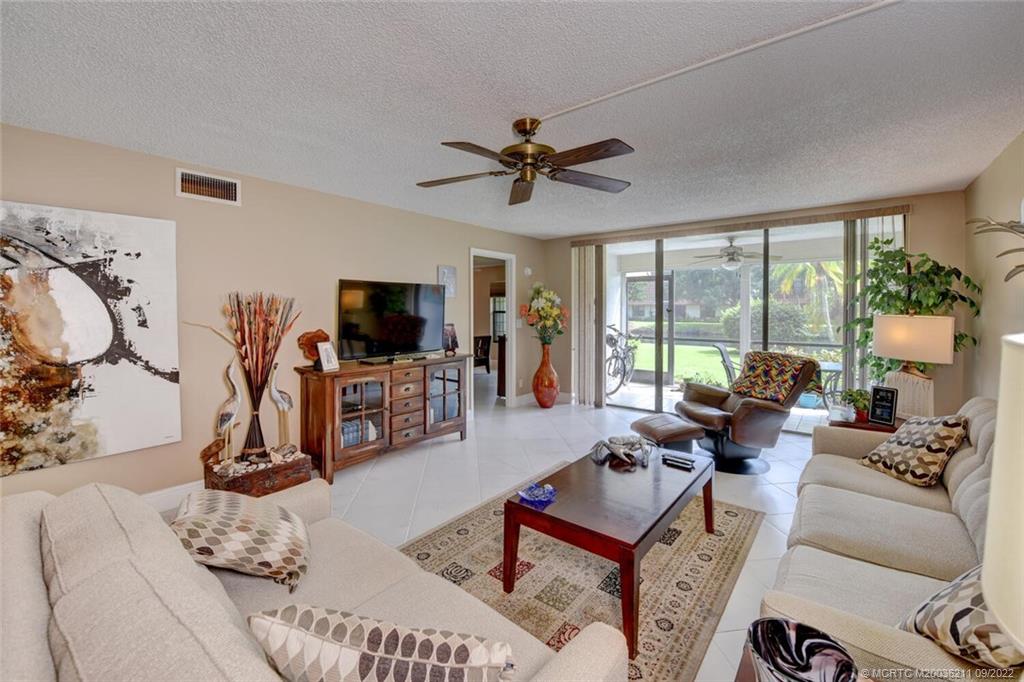 3100 Southeast Pruitt Road, Unit B102 Port St. Lucie, FL 34952 - Photo 17 of 55 a living room with furniture a flat screen tv and a large window