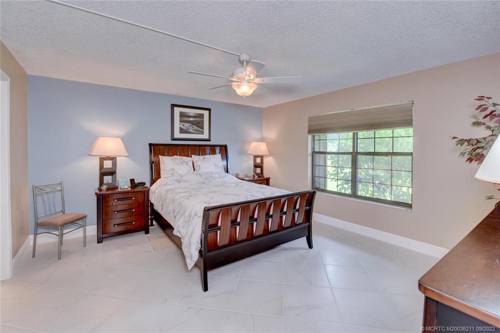 3100 Southeast Pruitt Road, Unit B102 Port St. Lucie, FL 34952 - Photo 24 of 55 a bedroom with a large bed and a chandelier