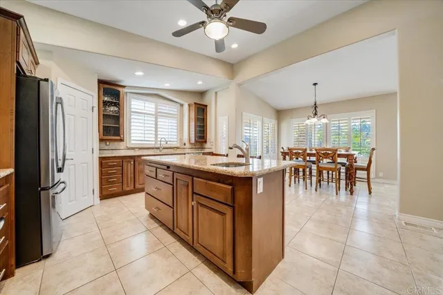 a kitchen with stainless steel appliances granite countertop a table chairs sink and cabinets