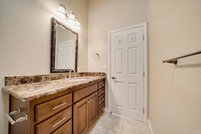 a bathroom with a granite countertop sink and a mirror