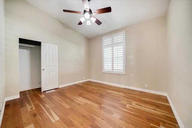 a view of empty room with wooden floor and fan