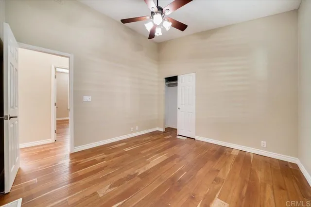 an empty room with wooden floor closet fan and windows