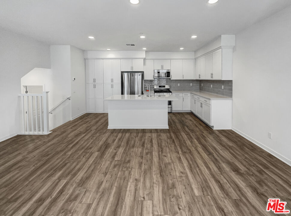 402 Echo Blue Lake Forest, CA 92610 - Photo 9 of 18 a large kitchen with kitchen island a sink dishwasher a stove and white cabinets with wooden floor