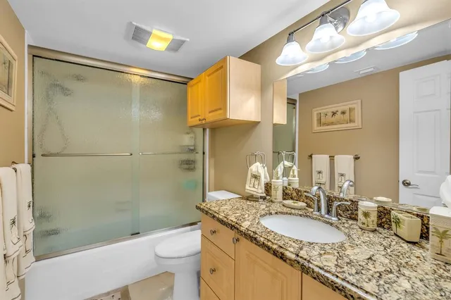 a bathroom with a granite countertop double vanity sink mirror and toilet