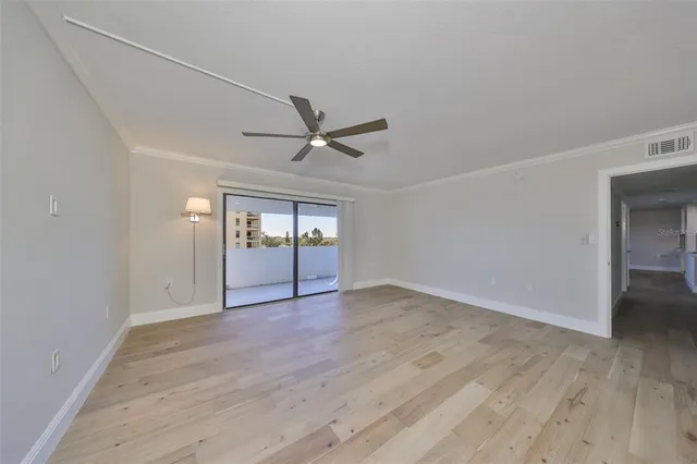 an empty room with wooden floor mirror and windows