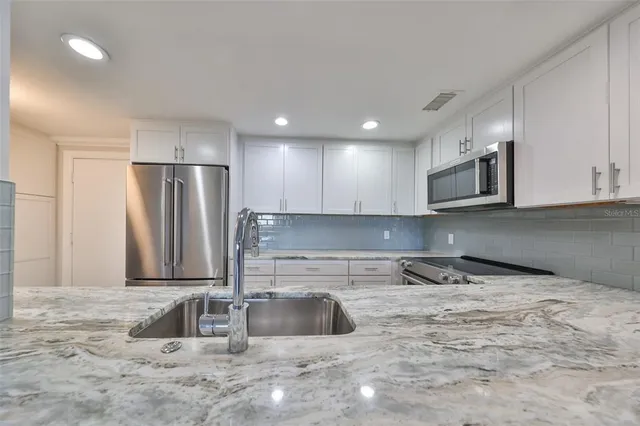 a kitchen with stainless steel appliances granite countertop a sink and a refrigerator